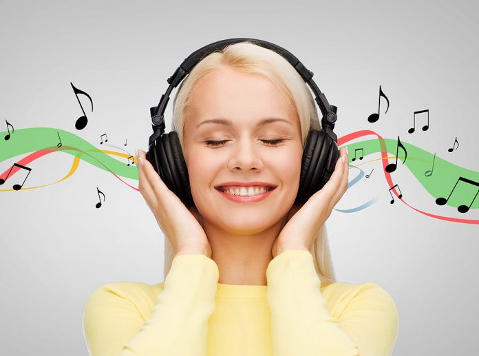 music and technology concept - smiling young woman with closed e