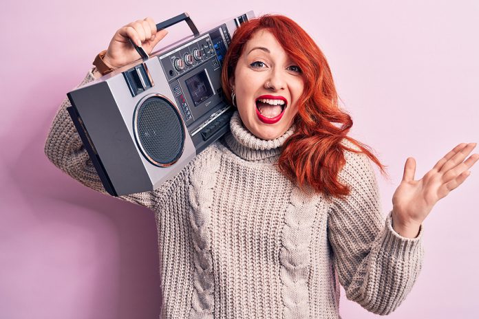 Beautiful redhead woman listening to music holding vintage boomb