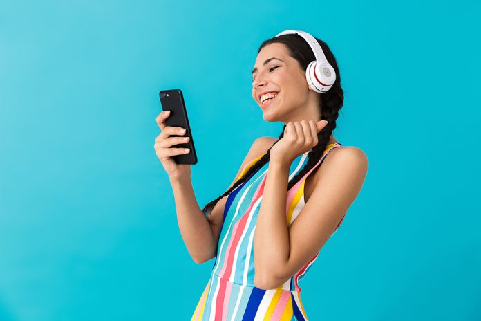 Image of nice happy woman with pigtails using headphones and mak
