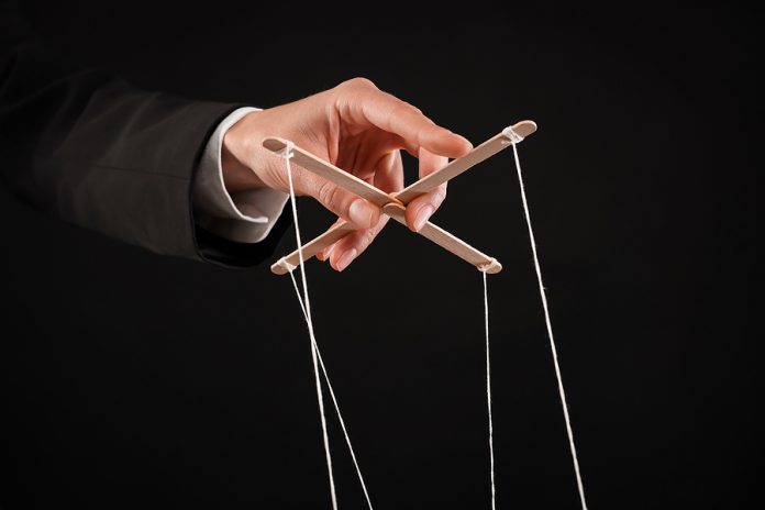 Woman Pulling Strings Of Puppet On Black Background, Closeup