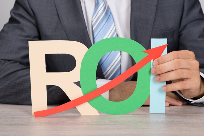 Businessman Holding Roi With Upward Moving Arrow