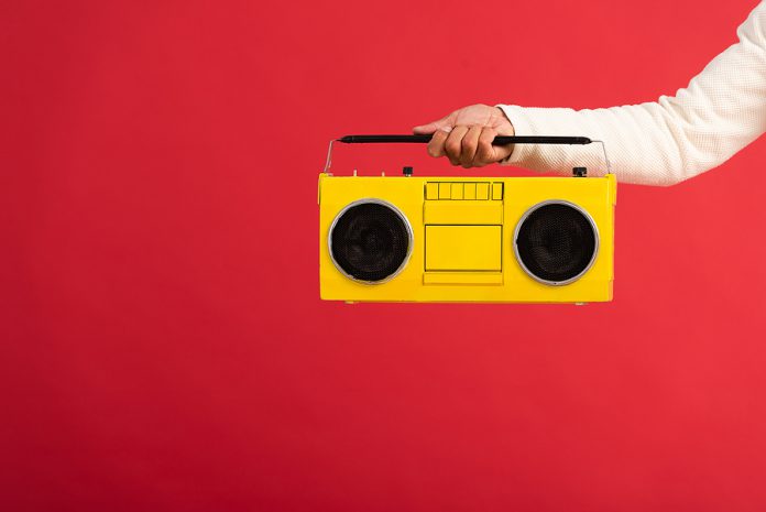 Cropped View Of Man Holding Yellow Boombox Isolated On Red