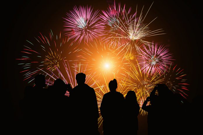 Crowd Watching Fireworks And Celebration. Happy Family Sitting O