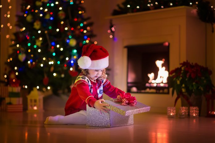Kids Opening Christmas Presents At Fireplace