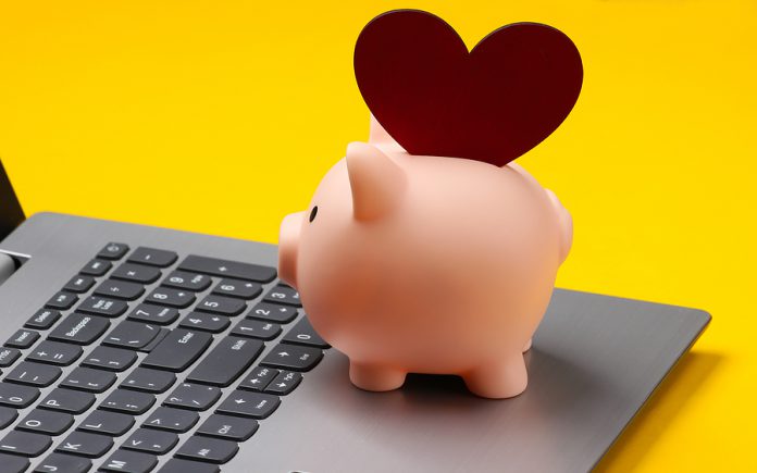 Laptop, Piggy Bank With Heart On Yellow Background.