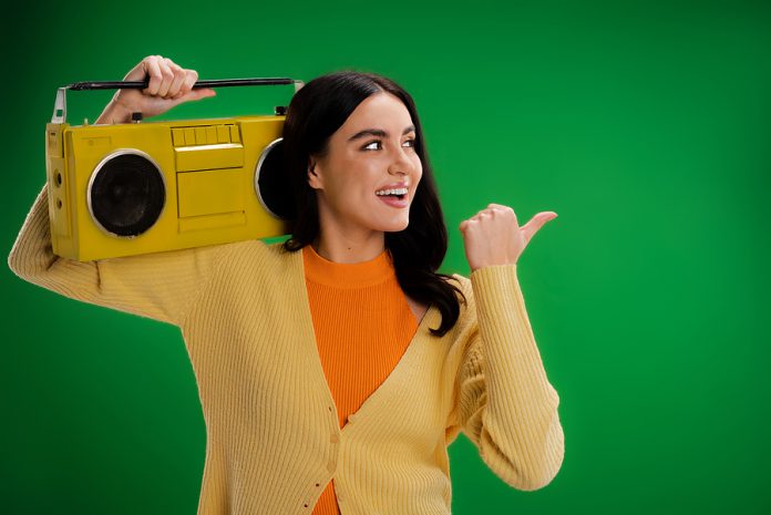 Smiling Woman With Vintage Boombox Looking Away And Pointing Wit