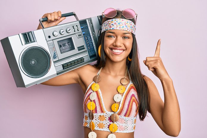 Beautiful hispanic woman wearing hippie style holding boom box s