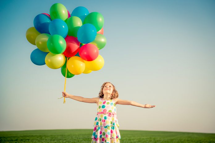 Happy Child Playing Outdoors In Spring Field