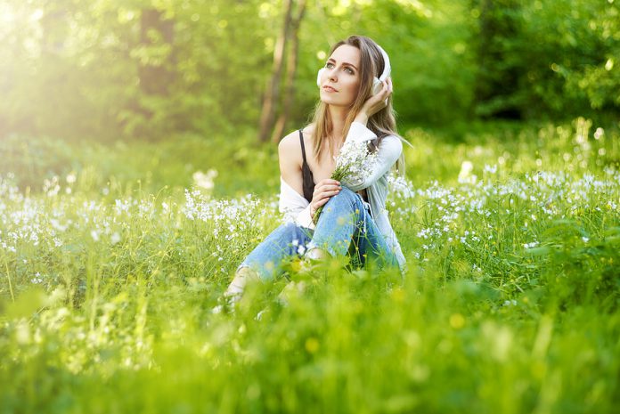 Happy Young Woman Sitting Outside On Fresh Green Spring Grass En