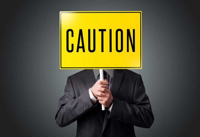 Businessman standing and holding a yellow caution sign in front