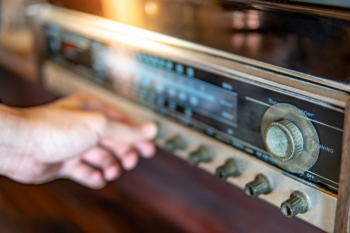 Male Hand Turning Retro Radio Button. Listen To Music Or News Wi