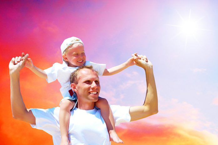 Joyful father giving piggyback ride to his son against a sky bac