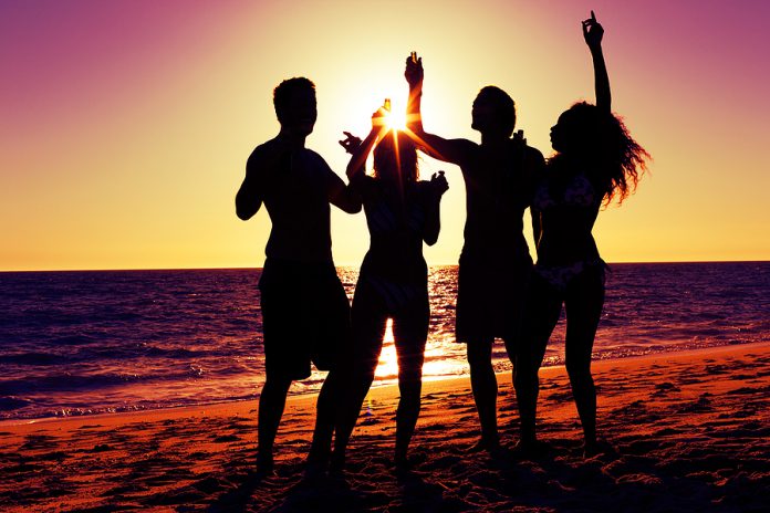 People (two couples) on the beach having a party, drinking and h