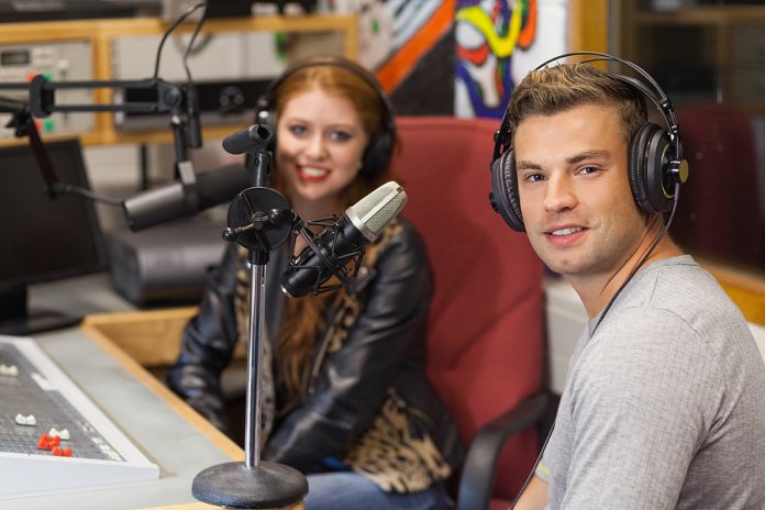 Attractive cheerful radio host interviewing a guest in studio at