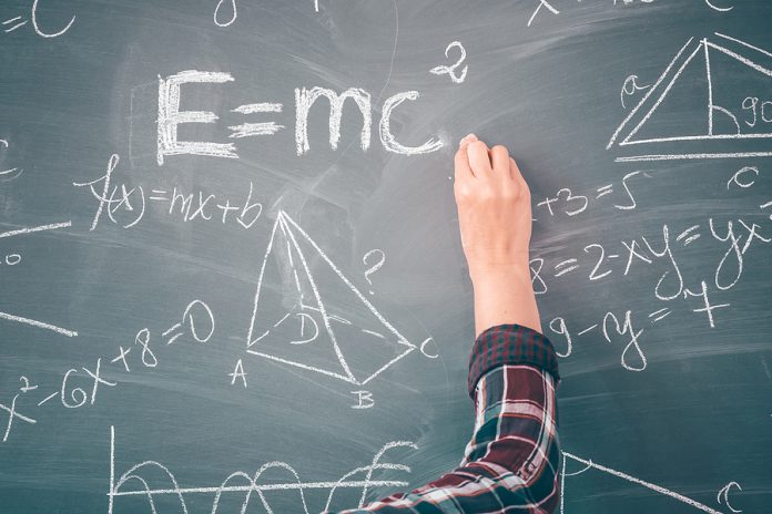 Close-up shot of a hand holding chalk and writing mathematical e