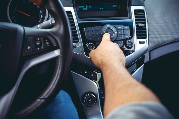 Car dashboard. Radio closeup. Man sets radio