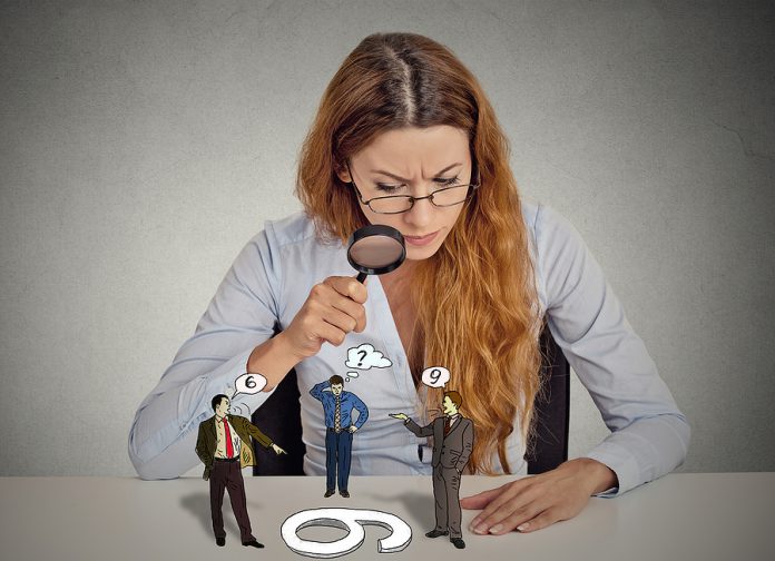Businesswoman With Glasses Sitting At Desk Skeptically Looking A