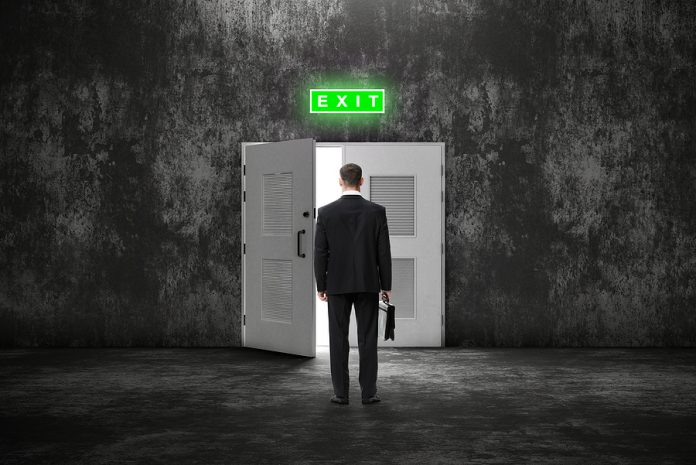 Backview of businessman with case before an open door to a brigh