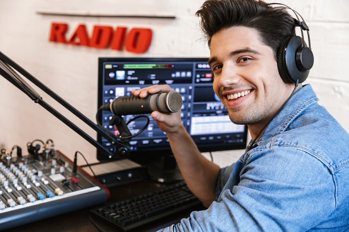 Handsome happy young male radio host broadcasting in studio, usi