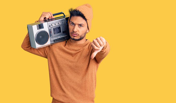 Handsome latin american young man holding boombox, listening to