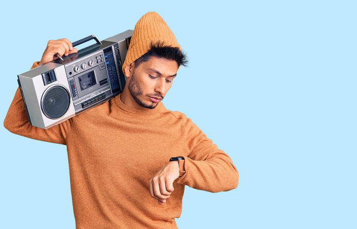 Handsome latin american young man holding boombox, listening to