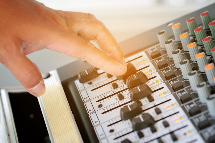 Man's Hand Is Adjusting The Music Volume From The Amplifier.
