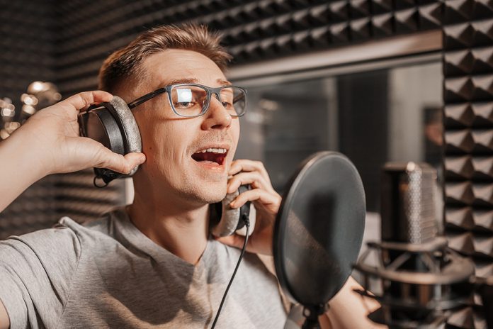 The Vocalist Sings In The Studio In A Microphone. Man In Headpho