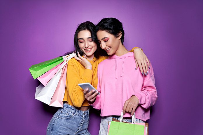 Two Happy Women Friends Shoppers Holding Shopping Bags Using Mob
