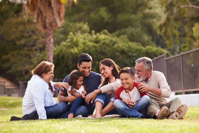 Happy three generation Hispanic family sitting on the grass toge