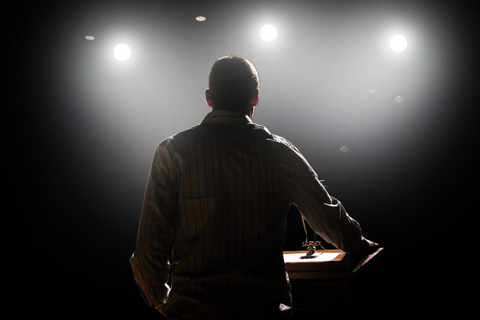 a young man in front of a podium and an audience